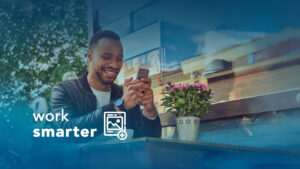 man looking at phone smiling outside by flower